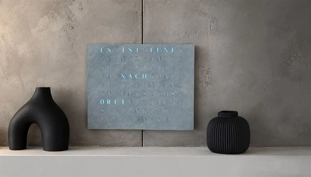 Graublaue WordClock zwischen schwarzen Vasen