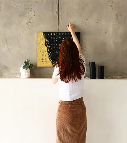 Frau bringt Wortuhr an der Wand an